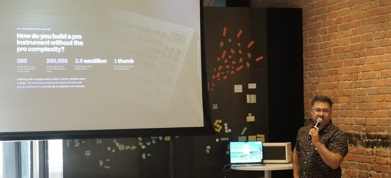A speaker beside a projected slide reading how do you build a pro instrument without the pro complexity.