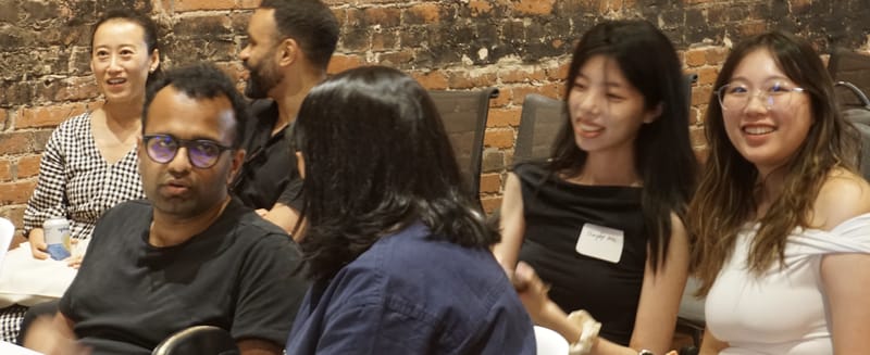 Attendees seated close together in the front rows, mid conversation.