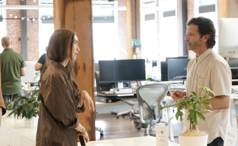 Two attendees talking beside the desks in the Pioneer Square Labs workspace.