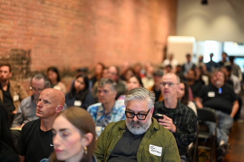 A dense seated audience several rows deep, watching a presentation.
