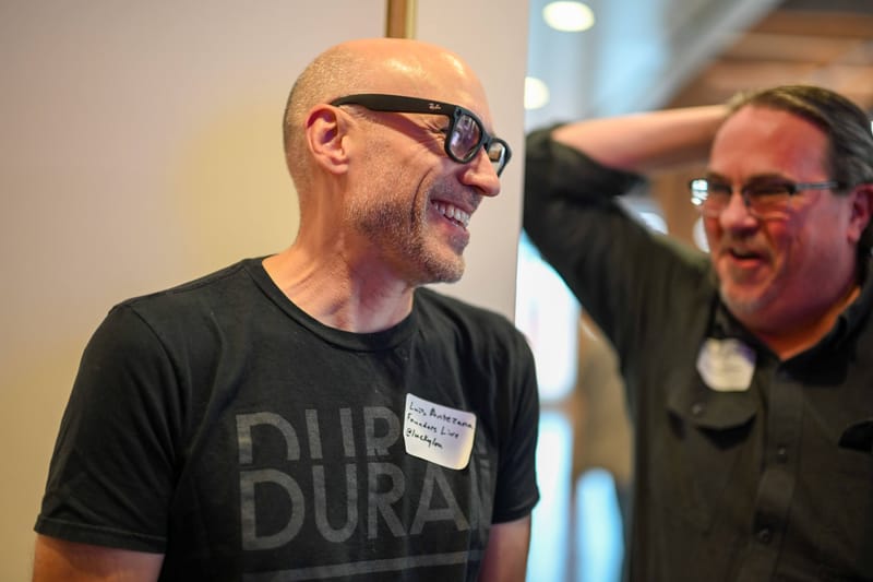 Two attendees laughing together, one with a hand behind his head.